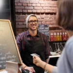 barman and woman paying with credit card at cafe